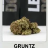 Gruntz Strain cannabis buds by Moonrock Online Shop – neon green buds with purple hues, sticky trichomes, and tropical fruit-themed packaging.