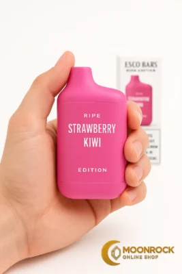 Hand holding a Strawberry Kiwi Esco Bars Ripe Edition disposable vape with box softly blurred in the background
