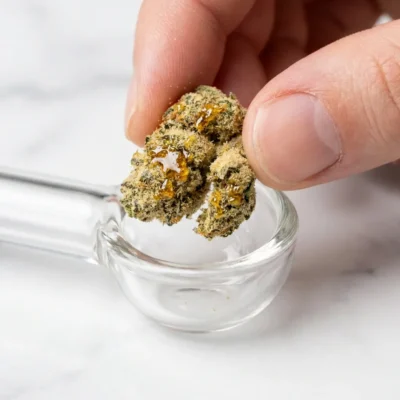 Small piece of premium sunrock being placed into a glass pipe bowl for controlled dosing
