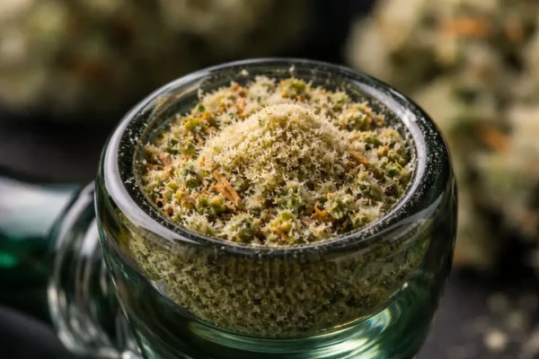 Glass bowl packed with ground cannabis and topped with a layer of golden kief