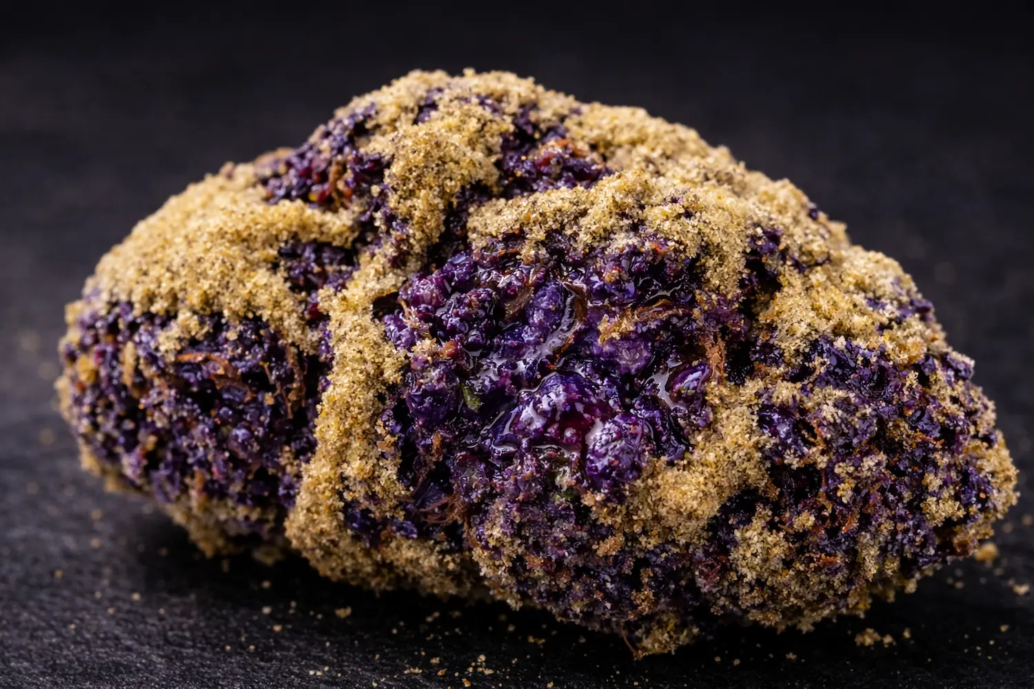 Close up of real purple moon rocks bud showing thick golden kief coating and sticky purple cannabis flower underneath